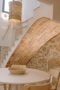 La Vila Hort by Seaward Suites في فايلاجويوسا: غرفة مع طاولة ودرج مع جدار حجري