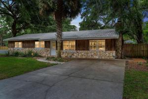 ein Haus mit einer Steinfassade und einem Baum in der Unterkunft Charming Cottage With Pool Table 15 Min From WEC in Ocala