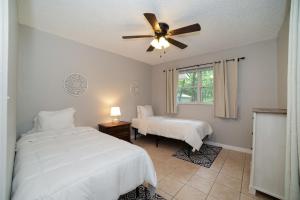ein Schlafzimmer mit zwei Betten und einem Deckenventilator in der Unterkunft Charming Cottage With Pool Table 15 Min From WEC in Ocala