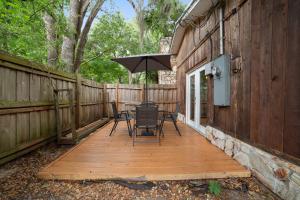 una terrazza in legno con tavolo, sedie e ombrellone di Charming Cottage With Pool Table 15 Min From WEC a Ocala