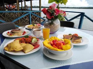 a table with plates of breakfast foods and a vase of flowers at Vista Mar Hotel  in Bocas Town