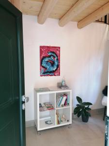a white book shelf in a room with a painting on the wall at VERDEPOESIA in Chioggia