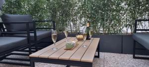 una mesa de madera con copas de vino en el patio en En hyper centre, logement climatisé entièrement rénové! Netflix - Amazon Prime - Terrasse - Le Nature Zen, en Surgères