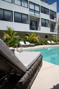 einen Pool mit einem Liegestuhl neben einem Gebäude in der Unterkunft Kiin Tulum, Luxury Suites in Tulum