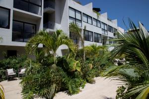 a building with palm trees in front of it at Kiin Tulum, Luxury Suites in Tulum