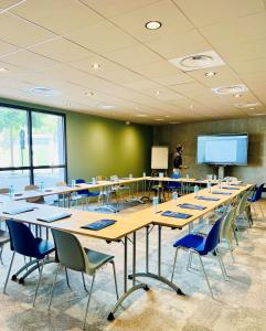 uma sala de aula com mesas e cadeiras e uma tela de projeção em Campanile Saint Brieuc - Centre Gare em Saint-Brieuc