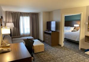 a hotel room with a bedroom and a bed and a desk at Staybridge Suites - Calgary Airport, an IHG Hotel in Calgary