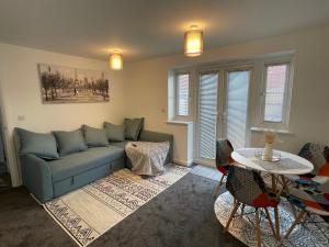 a living room with a blue couch and a table at Aspen Villa, Apsley Station in Hemel Hempstead