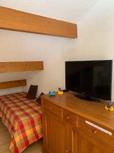 a bedroom with a flat screen tv on a wooden dresser at Pied des pistes, pleine nature in Ustou