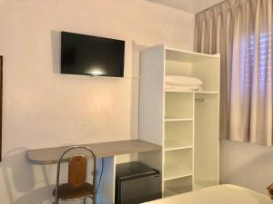 um quarto com uma secretária e uma televisão na parede em Hotel Concatto em Farroupilha