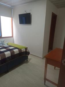 a bedroom with a bed and a tv on the wall at Hotel Las Palmas de Puente Nacional in Puente Nacional