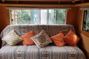 a couch with pillows on it in front of a window at L'hermitage d'Apollon au sein d'un jardin forêt près de l'océan in Mimizan