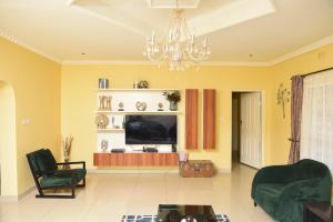 a living room with a television and a chandelier at AZB Cozy Homes. Elegant 4 bedroom home in Area 49, Lilongwe in Lilongwe