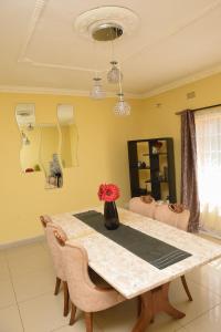 einen Esstisch mit einer Blumenvase darauf in der Unterkunft AZB Cozy Homes. Elegant 4 bedroom home in Area 49, Lilongwe in Lilongwe