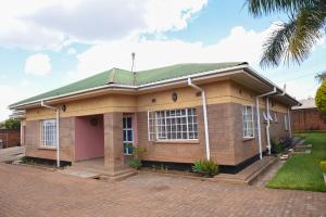 ein Haus mit grünem Dach in der Unterkunft AZB Cozy Homes. Elegant 4 bedroom home in Area 49, Lilongwe in Lilongwe