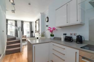 a kitchen with white cabinets and pink flowers on the counter at GuestReady - Stunning Covent Garden 2BR Duplex in London