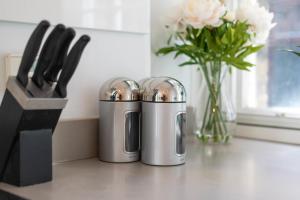two silver containers sitting on a counter with a vase of flowers at GuestReady - Stunning Covent Garden 2BR Duplex in London