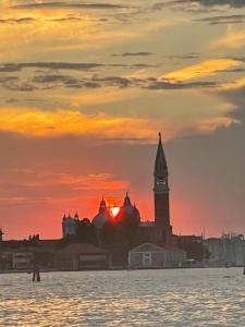 een zonsondergang boven een stad met een klokkentoren bij Ca' ai Sospiri in Venetië