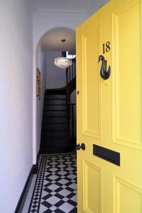 eine gelbe Tür im Flur mit schwarzweißem Boden in der Unterkunft Menagerie House Luxury City Cottage, Walk Score 98 in York