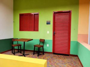 Habitación con puertas rojas, mesa y 2 sillas en Atelier & Pousada Chapada, en Alto Paraíso de Goiás