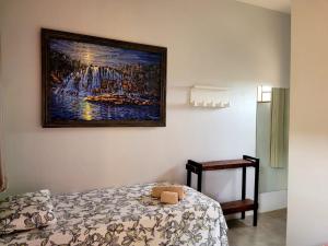 Un dormitorio con una pintura en la pared y una cama en Atelier & Pousada Chapada, en Alto Paraíso de Goiás