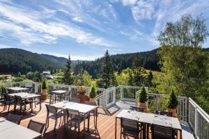 a deck with tables and chairs on a balcony at Spa hotel Lanterna in Velké Karlovice