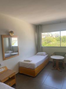 1 dormitorio con cama, espejo y mesa en Aquamarine Hotel en Eilat