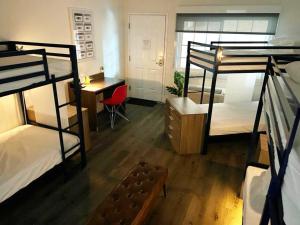 a room with three bunk beds and a desk and a deskablishthritisthritisthritis at Bposhtels Anaheim in Anaheim