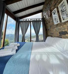 Complejo Rural Lar de Vies في A Pontenova: غرفة نوم بسرير ونوافذ كبيرة