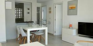 ein Wohnzimmer mit einem weißen Tisch und einem TV in der Unterkunft Sunnybeach Apartment mit direktem Strandzugang in Denia