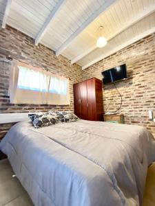 1 dormitorio con 1 cama grande en una pared de ladrillo en Las Marías en Azcuénaga
