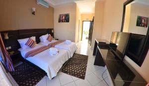 a bedroom with two beds and a flat screen tv at Hotel Al Akha in Sidi Harazem