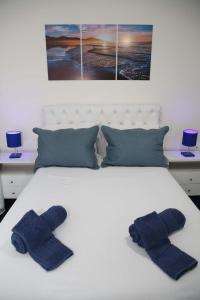 dois chinelos azuis numa cama branca com dois quadros em Elegante Duplex Oceanico da Elena Super Cozinha USP y UfSCAR em São Carlos