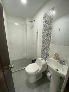 y baño con aseo, lavabo y ducha. en HOTEL PLAZA BOLIVAR MOMPOX ubicado en el centro histórico con parqueadero interno, en Mompox