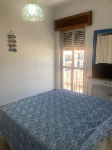 a bedroom with a bed and a tv and a window at Hotel L'Ancora in La Caletta
