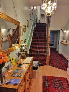 Habitación grande con escalera, mesa y lámpara de araña. en Dunallan Guest House, en Perth
