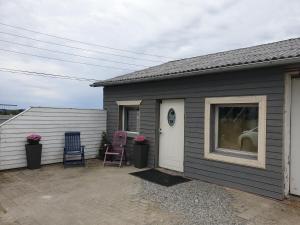 a gray house with two chairs and a window at Comfortable apartment, 10min Airport in Stavanger +3 photos