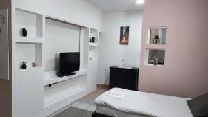 a white room with a bed and a flat screen tv at Airport Apartment AIR in Surčin