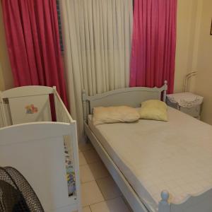 a small bedroom with a bed and pink curtains at Γκρι βιλλα 2 in Periyiálion