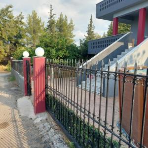 a black fence with red gates in front of a building at Γκρι βιλλα 2 in Periyiálion