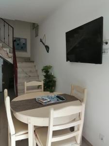 a dining room table with chairs and a television on a wall at Casa das Andorinhas in Lagos
