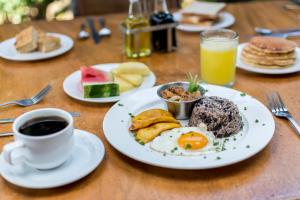 a table with a plate of breakfast food and a cup of coffee at Rinconcito Lodge in Liberia