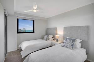 a white bedroom with two beds and a window at Panoramic Ocean View 2 bed 2 bath in Alexandra Headland