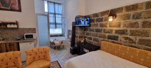 1 dormitorio con pared de piedra, 1 cama y 2 sillas en Sanabl Druze Hospitality, en Ein Kinya