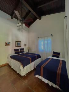 a bedroom with two beds and a ceiling fan at Hacienda La Esperanza in Copan Ruinas