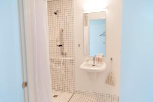 uma casa de banho com um lavatório e um chuveiro com um espelho. em Travelers New Orleans em Nova Orleães