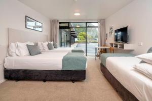 a bedroom with two beds and a flat screen tv at The Com Plex Motel in Whakatane