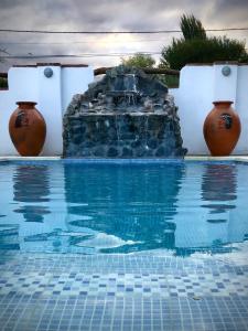 a swimming pool with a water fountain next to vases at Refugios del Callejón in San Carlos