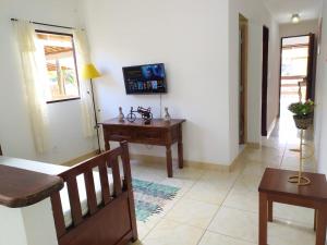 un soggiorno con tavolo e TV a parete di Casa Próximo do Centro a Parati