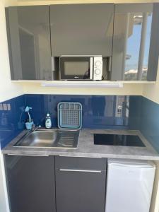 a kitchen with a sink and a microwave at Appartement piscine et vue mer in Tartane